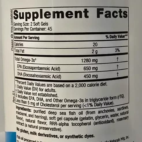 Nordic Naturals Ultimate Omega bottle open with soft gel capsules on a wooden surface in warm light