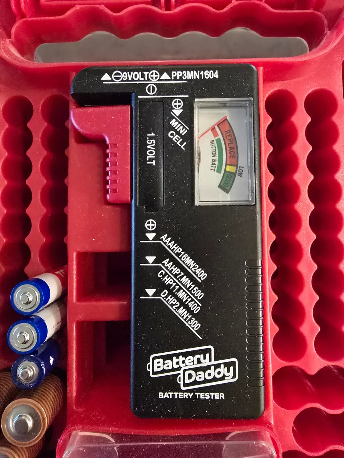 Close-up of the built-in battery tester gauge with a AA battery inserted for testing